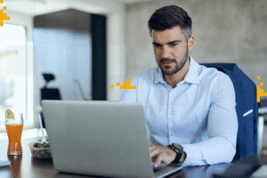 Homem trabalhando em um escritório com laptop, representando uma plataforma de cursos para empresas, promovendo aprendizado corporativo e capacitação.